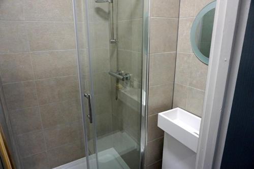 a shower with a glass door next to a sink at Townsend lane accommodation in Liverpool