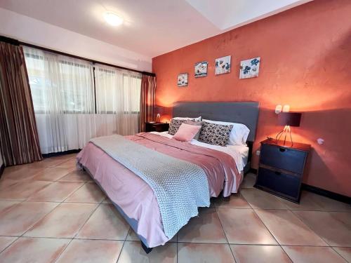 1 dormitorio con 1 cama con pared de color naranja en Beautiful home w/ backyard, AC - close to airport, en Brasil