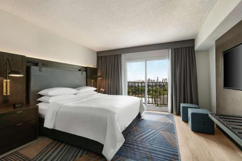 a hotel room with a large bed and a balcony at Embassy Suites by Hilton Los Angeles Downey in Downey