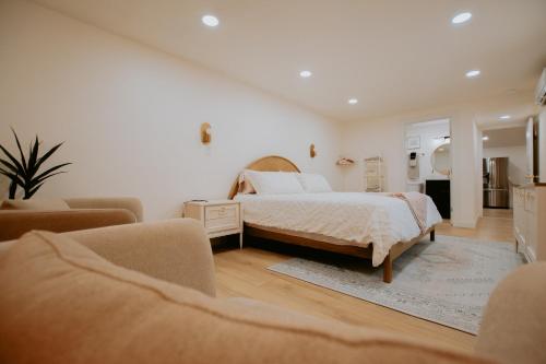 a white bedroom with a bed and two chairs at East Downtown Desert Chic Casita-Hot Tub-Pet Friendly-No Pet Fees! in Albuquerque