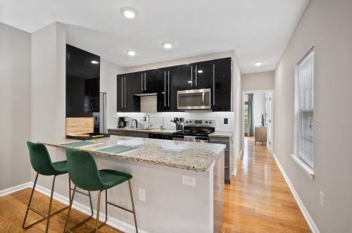 una cocina con armarios negros y una barra con sillas verdes en StayRafa At 261 4R en Filadelfia