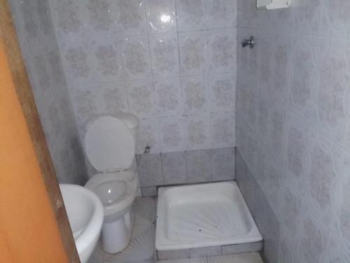 een badkamer met een wit toilet en een wastafel bij Hospedaria Zac in Luanda