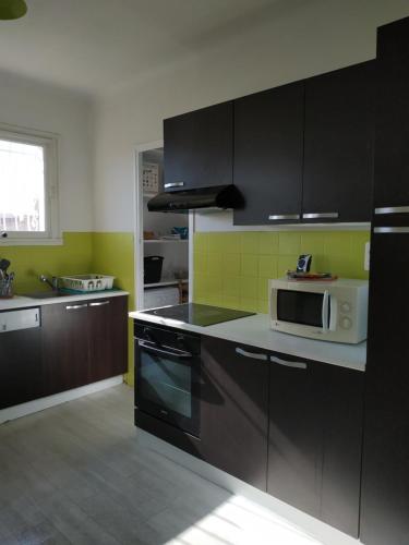 - une cuisine avec des armoires noires et un four micro-ondes blanc dans l'établissement Ondine Vacances, à Six-Fours-les-Plages