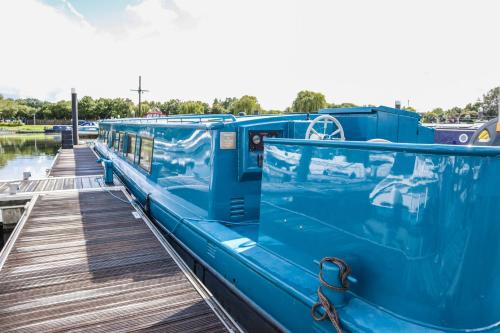 a blue boat is docked at a dock at Blue Waterside Haven Charming 2 Bedroom Boat on Staines Rd Chertsey in Chertsey