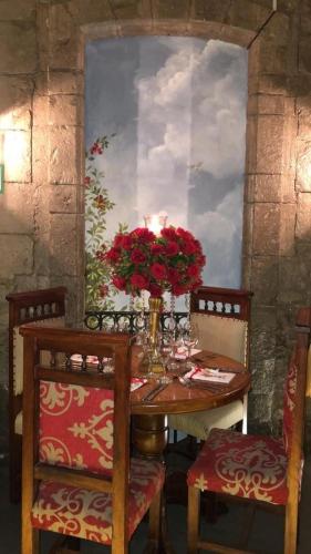 a table with a vase of red flowers on it at Roka Plaza Hotel Boutique in Ambato
