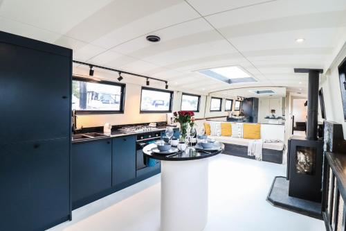 a kitchen with blue cabinets and a table in a room at Blue Waterside Haven Charming 2 Bedroom Boat on Staines Rd Chertsey in Chertsey