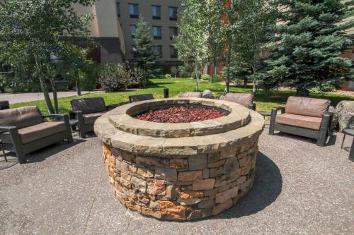 a stone fire pit in a park with chairs and trees at Homewood Suites by Hilton Bozeman in Bozeman