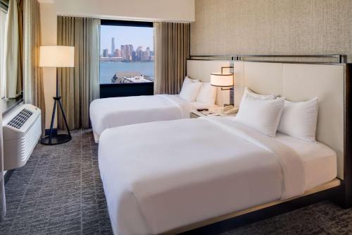 two beds in a hotel room with a window at DoubleTree by Hilton Hotel & Suites Jersey City in Jersey City