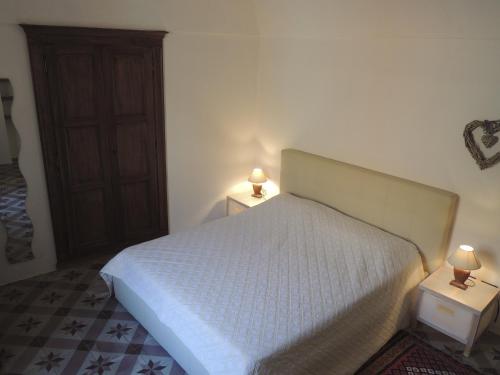 a bedroom with a white bed and two tables with lamps at La Casa Di Cocca in Alba
