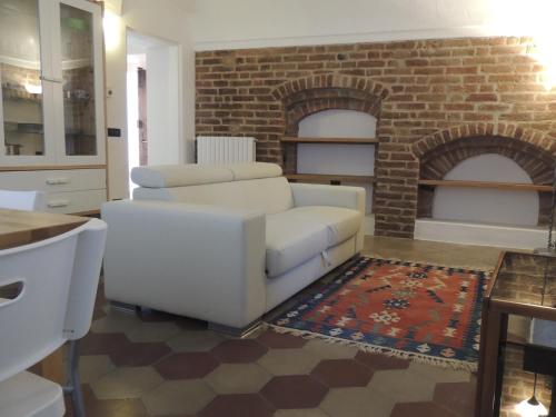 a living room with a white couch and a brick fireplace at La Casa Di Cocca in Alba