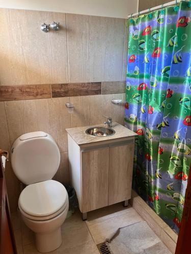 a bathroom with a toilet and a shower curtain at Dtos las brisas in La Banda