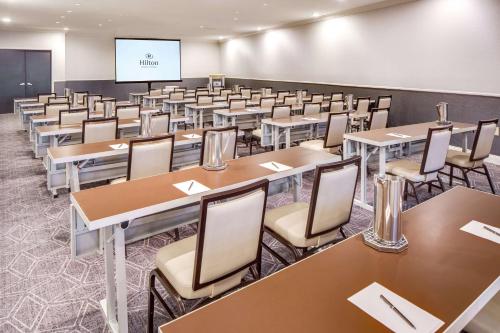 a classroom with tables and chairs and a screen at Hilton Newark Airport in Elizabeth