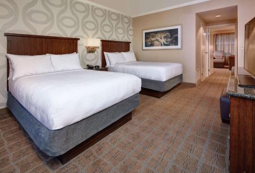 a hotel room with two beds and a television at Embassy Suites by Hilton San Diego La Jolla in San Diego