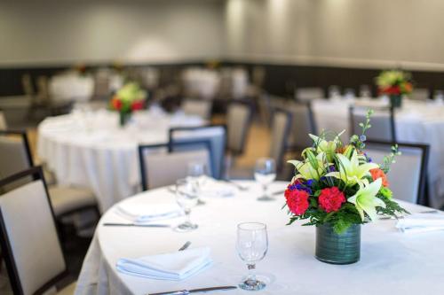 a room with white tables with a vase of flowers at Hilton Newark Airport in Elizabeth