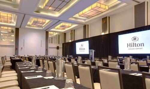 a conference room with tables and chairs and screens at Hilton Newark Airport in Elizabeth