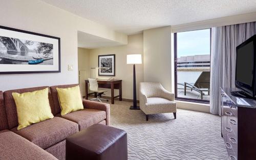 a living room with a couch and a television and a desk at DoubleTree by Hilton Washington DC – Crystal City in Arlington