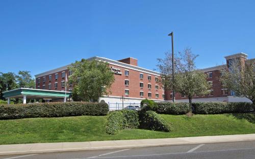 a large brick building with bushes in front of a street at Hampton Inn & Suites By Hilton - Rockville Centre in Rockville Centre