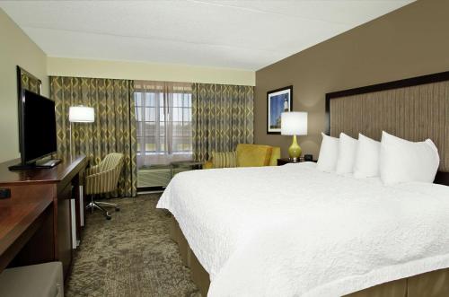 a hotel room with a large bed and a television at Hampton Inn & Suites By Hilton - Rockville Centre in Rockville Centre