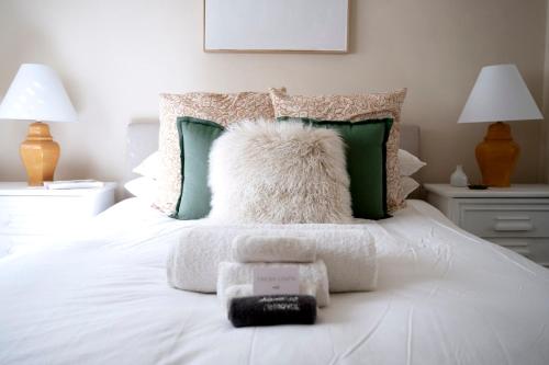 ein Bett mit einem weißen Kissen und grünen Kissen in der Unterkunft Popular Central Location I NEW LINEN I Gated Estate I STAY DUBBO in Dubbo
