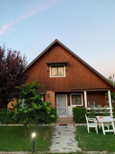 Une grange rouge avec une table blanche et des chaises devant elle dans l'établissement Vila 10 Fshati Turistik - Ishull Lezhe, Kune Vain, à Lezhë