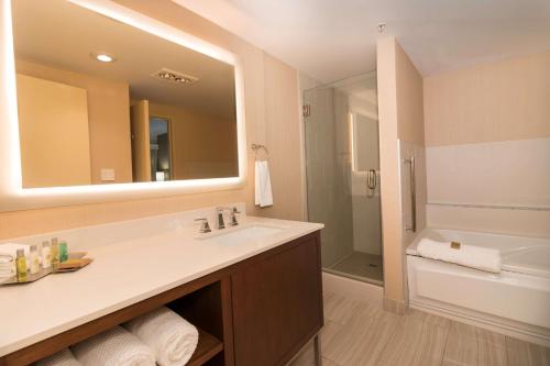 DoubleTree by Hilton Spokane City Center في سبوكان: حمام مع حوض ومرآة كبيرة