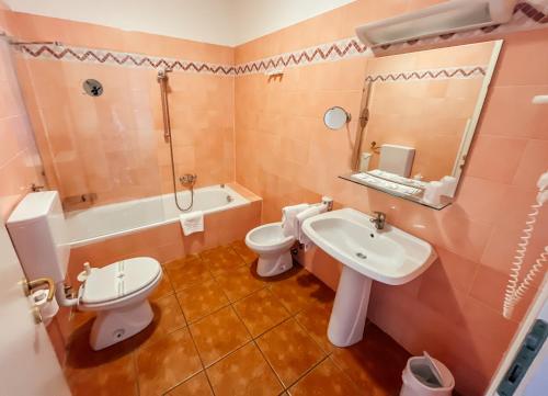 a bathroom with two toilets and a sink and a tub at Caroline Hotel in Brusimpiano