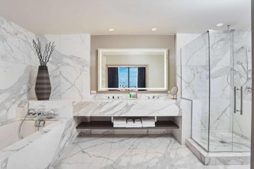 a white bathroom with a sink and a shower at Hilton West Palm Beach in West Palm Beach