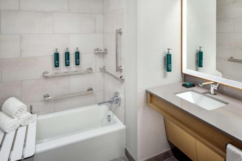 y baño con bañera blanca, lavabo y espejo. en Hilton Columbus Downtown, en Columbus