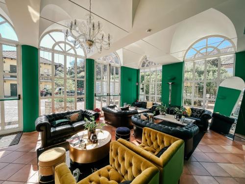 a large room with couches and tables and windows at Caroline Hotel in Brusimpiano