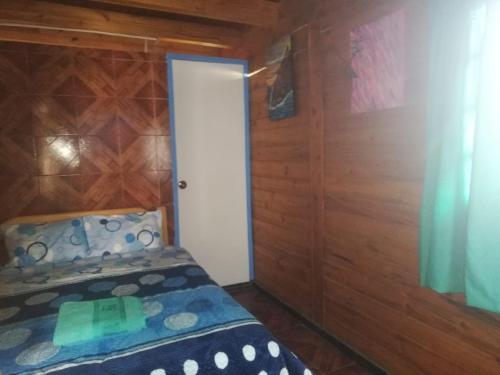 1 dormitorio con 1 cama y pared de madera en SHERANPAZ, en Oxapampa