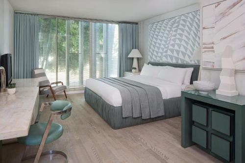 a bedroom with a large bed with a desk and a chair at Avalon Hotel Beverly Hills, a Member of Design Hotels in Los Angeles