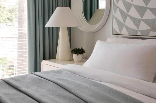 a bedroom with a bed with a lamp and a mirror at Avalon Hotel Beverly Hills, a Member of Design Hotels in Los Angeles