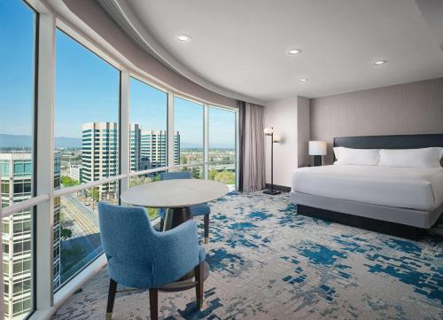 a hotel room with a bed and a table and windows at Hilton San Jose in San Jose