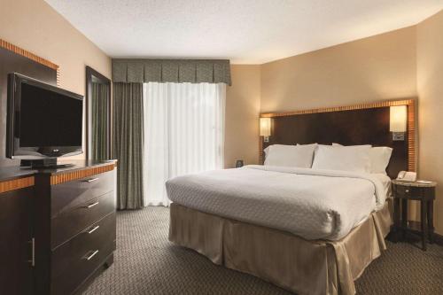 a hotel room with a bed and a flat screen tv at Embassy Suites Birmingham in Birmingham