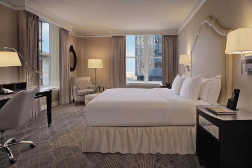 um quarto de hotel com uma grande cama branca e uma secretária em The Skirvin Hilton Oklahoma City em Oklahoma City