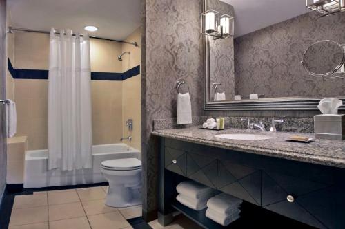 a bathroom with a sink and a toilet and a mirror at The Skirvin Hilton Oklahoma City in Oklahoma City