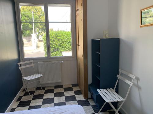 Cette chambre comprend un lit, une chaise et une fenêtre. dans l'établissement Maison de vacances Arzaël à 200m de la plage célèbre de Mr Hulot, à Saint-Nazaire