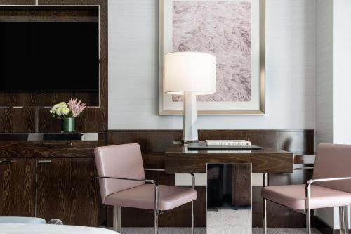 a hotel room with a desk with a television and pink chairs at Waldorf Astoria Las Vegas in Las Vegas