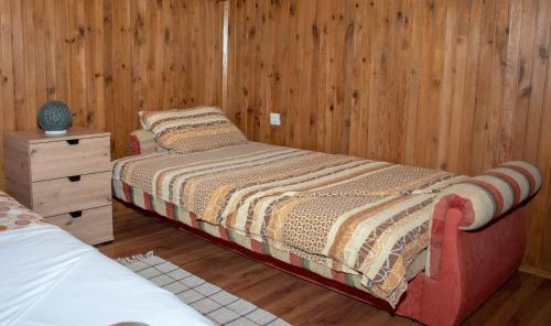 a bedroom with a bed and a wooden wall at Raj na selu - Padaberi paradise in Berane