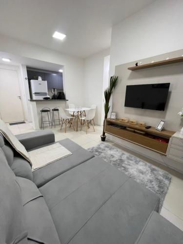 een woonkamer met een bank en een flatscreen-tv bij Apartamento em condomínio 24 hrs in Juazeiro do Norte