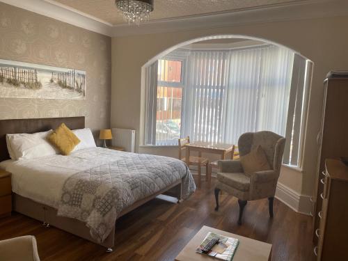 a bedroom with a bed and a chair and a window at San Remo Apartments in Blackpool