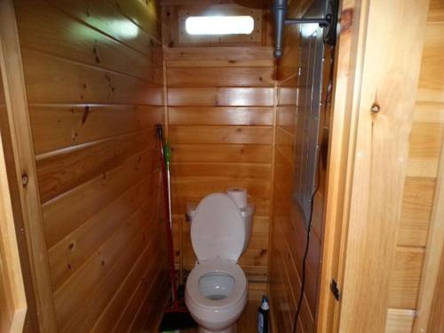 a small bathroom with a toilet in a wooden wall at Rustic Lakefront Cottage Derby Paddles Lodge in Derby Center