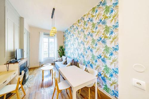 een woonkamer met een tafel en stoelen en een muur bij Le Tolstoï charmant 4 pers Villeurbanne in Villeurbanne