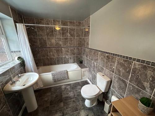a bathroom with a tub and a toilet and a sink at Modern & Bright 4 Bedroom Home in Stoke on Trent