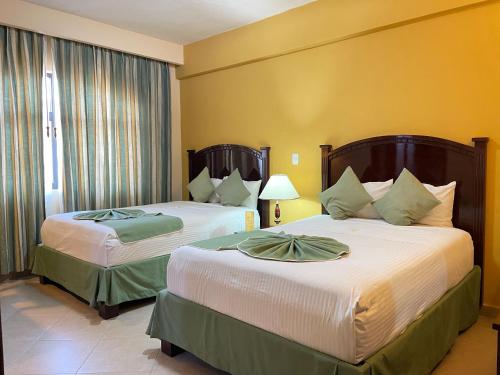 2 Betten in einem Hotelzimmer mit gelben Wänden in der Unterkunft Hotel Centenario in Iguala de la Independencia