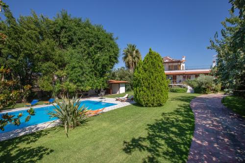 a yard with a swimming pool and trees and a building at KORALIA MARATHON VILLA in Nea Makri