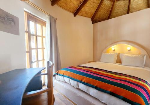 Schlafzimmer mit einem Bett, einem Tisch und einem Fenster in der Unterkunft Hotel Tulor in San Pedro de Atacama