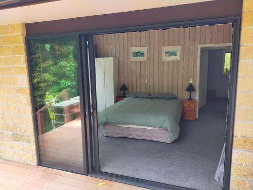 a bedroom with a bed and a sliding glass door at Maitai Whare Iti - Adventure Cabins & House in Nelson