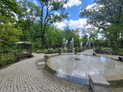 a fountain in a park with benches and trees at Aquarius Kilińskiego szafir in Grodzisk Mazowiecki