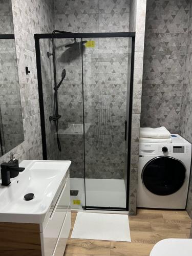 a bathroom with a shower and a washing machine at Aquarius Kilińskiego szafir in Grodzisk Mazowiecki